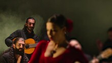 Beautiful Stylish Female Artist Dancing Spanish Style Dance . Group Of Men Playing On Guitar And Applauds To The Dancer Woman . Concept Footage Of Spanish Traditional Culture . Waving Cloth Of Skirt 