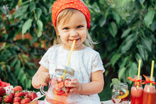 Lemonade Stand. Adorable Little Girl Trying To Sell Lemonade. Strawberry Lemonade With Ice And Mint As Summer Refreshing Drink In Jars. Cold Soft Drinks With Fruit. Child Drinking Smoothie In Jar
