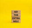 Go the extra mile symbol. Wooden blocks with words Go the extra mile. Beautiful yellow background. Business and Go the extra mile concept. Copy space.