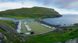 View of an old soccer field with a picturesque cliff on the coast near the village of Eidi in the Faroe Islands. This football stadium is now used as a campsite.