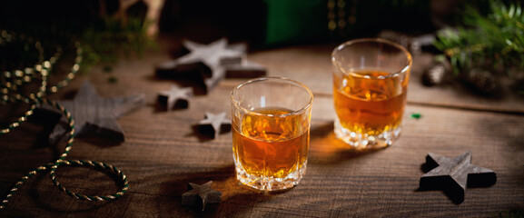 Whiskey, brandy or liquor shot and Christmas decorations on wooden background. Christmas holidays mood concept.