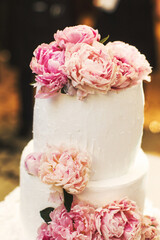 Wall Mural - Multilevel wedding cake on the table decorated with peonies