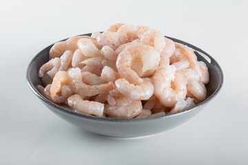 A bowl of peeled fresh raw white shrimp with tail.