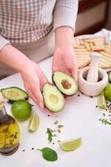 Wall Mural - Making avocado toast - Woman hold fresh ripe halved avocado