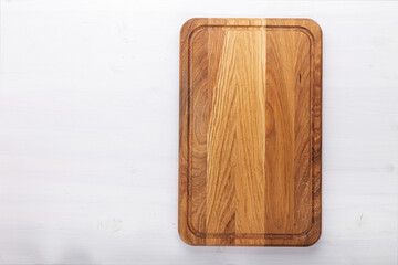 Wall Mural - Rectangular cutting board on a white wooden table. Food preparation tool and kitchen utensils.
