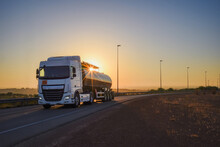 Tanker Truck With Dangerous Goods Driving Along A Lonely Road With The Sun In Backlight