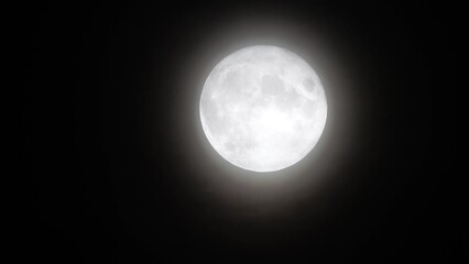 Wall Mural - Glowing huge full moon as seen from earth through the clouds against starry night sky. Large full moon moves across the sky, moon makes its way from bottom left frame to top right.