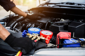 Close up hand of auto mechanic are to use measuring manifold gauge for filling car air conditioners. Concepts of fix and checking for repair service , Car service concept .