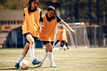 Wall Mural - Female players playing with ball during soccer training at stadium.