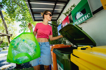 A young beautiful girl throws sorted garbage into special bins