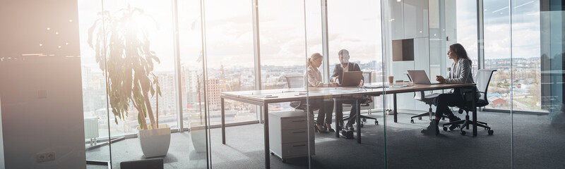 Wall Mural - Creative business people working on project in modern office with panoramic view. Blurred background