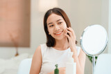 Fototapeta Na sufit - Closeup portrait of smiling young beautiful asian woman looking at mirror touching her skin enjoying treatment for dry skin. 