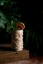 Dark And Moody Tiki Cocktail With Dried Fruit And Mint Garnish