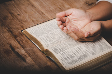 Wall Mural - Close up of christian woman hand on holy bible are pray and worship for thank god in church with black background, concept for faith, spirituality and religion