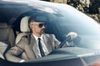 © gstockstudio - Confident mature man in formalwear and eyeglasses driving a car