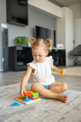 cute caucasian little girl playing on the floor at home with eco wooden toys. montessori toy. the ch