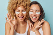 © wayhome.studio  - Skin care and beauty procedures concept. Cheerful overjoyed women apply white patches under eyes to reduce dark circles laugh gladfully stand closely to each other isolated over blue background