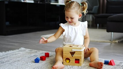 cute caucasian little girl playing on the floor at home with eco wooden toys. montessori toy. the ch
