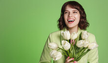 Laughing Woman Looking Happy, Holding Bouquet Of White Tulips. Happy Birthday Girl With Beautiful Flowers On Green Background