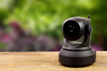 Black IP Camera on wooden with blur background. CCTV security camera for home or office.