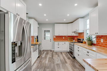 Wall Mural - modern kitchen interior white cabinets black hardware bold orange red subway backsplash tile hardwood floors wooden butchers counter tops french doors plants recessed lighting fixture stainless steel 