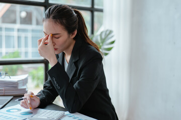 Young business woman stressed and headaches while working on laptop in office space.