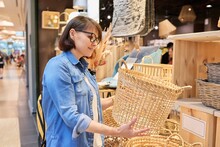 Mature Woman Shopper Choosing Interior Wicker Baskets In Home Decor Store