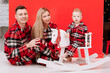 © Andriy Medvediuk - smiling young mom, dad are playing with baby boy on wooden rocking horse on the red background. happy family with little child in red checked pyjamas having fun together. Childcare, childhood
