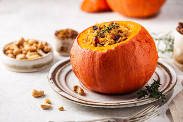 Poster - Tasty baked pumpkin stuffed with rice, vegetables, cashews and dried fruits on white background