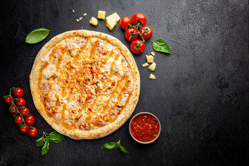 Poster - Tasty pizza with chicken and Sweet and sour sauce and cooking ingredients tomatoes and basil on black background. Top view