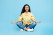 © Prostock-studio - Arabic Woman Meditating Sitting In Lotus Position Over Blue Background
