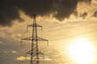 Silhouette of high voltage tower with electrical wires on background of sunset sky and dark clouds. Electricity transmission lines, power supply concept