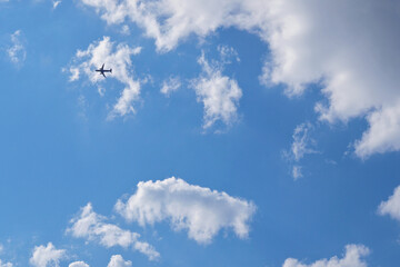 Wall Mural - The passenger airplane is flying far away in the blue sky and white clouds. Aircraft in the air. Light background or backdrop about international passenger air transportation