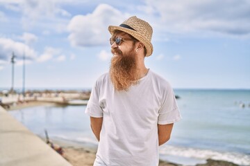 Wall Mural - Young redhead tourist man smiling happy standing at the beach.