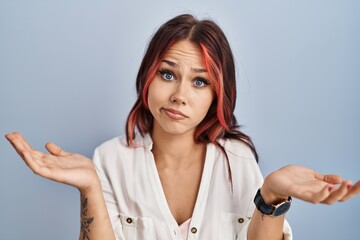 Sticker - Young caucasian woman wearing casual white shirt over isolated background clueless and confused expression with arms and hands raised. doubt concept.