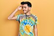 © Krakenimages.com - Young hispanic man wearing casual clothes very happy and smiling looking far away with hand over head. searching concept.