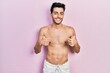 © Krakenimages.com - Young hispanic man wearing swimwear shirtless success sign doing positive gesture with hand, thumbs up smiling and happy. cheerful expression and winner gesture.