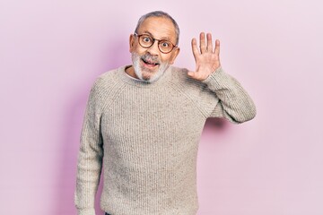 Wall Mural - Handsome senior man with beard wearing casual sweater and glasses waiving saying hello happy and smiling, friendly welcome gesture