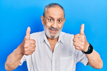 Wall Mural - Handsome senior man with beard wearing casual white shirt approving doing positive gesture with hand, thumbs up smiling and happy for success. winner gesture.