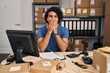 Hispanic man with curly hair working at small business ecommerce laughing and embarrassed giggle covering mouth with hands, gossip and scandal concept
