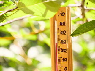 Red heat warning , Heatwave cause climate change and global warming . Weather Thermometer making 30 degrees celsius temperature , extreme hot summer in Hungary, Europe. Nature green forest background.