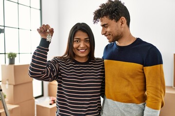 Poster - Young latin couple smiling happy and hugging holding key of new home.