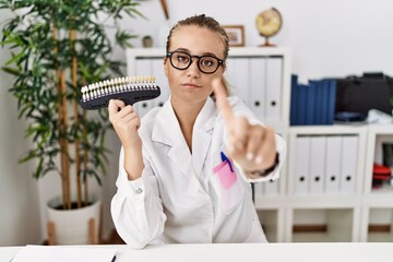 Canvas Print - Young caucasian woman holding teeth whitening palette pointing with finger up and angry expression, showing no gesture