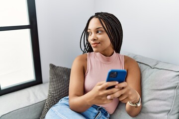 Poster - Young african american woman smiling confident using smartphone at home