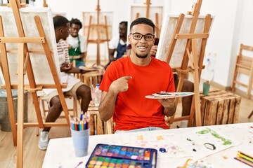 Canvas Print - Young african man at art studio pointing finger to one self smiling happy and proud