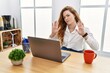 Young caucasian woman working at the office using computer laptop moving away hands palms showing refusal and denial with afraid and disgusting expression. stop and forbidden.