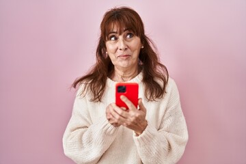 Sticker - Middle age hispanic woman using smartphone typing message smiling looking to the side and staring away thinking.