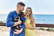 © Krakenimages.com - Young caucasian couple smiling happy and hugging with dog at the beach.