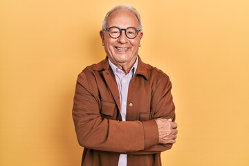 Senior man with grey hair wearing casual jacket and glasses happy face smiling with crossed arms looking at the camera. positive person.