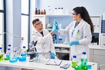 Poster - Man and woman wearing scientist uniform high five with hands raised up at laboratory